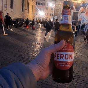 Sujetando una botella de 66cl de Peroni de noche en Roma