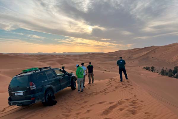 El grupo junto al 4x4 en la cima d euna duna al atardecer
