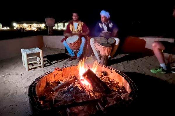 par de bereberes cantando y tocando los tambores en la hoguera en el hoyel de jaimas por la noche, el Sáhara, Marruecos